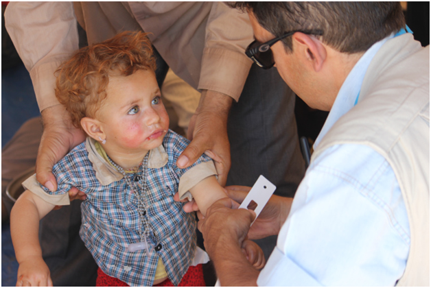 un travailleur de la santé de l’UNICEF mesure le bras d’un jeune enfant yézidi dans le cadre d’une évaluation nutritionnelle