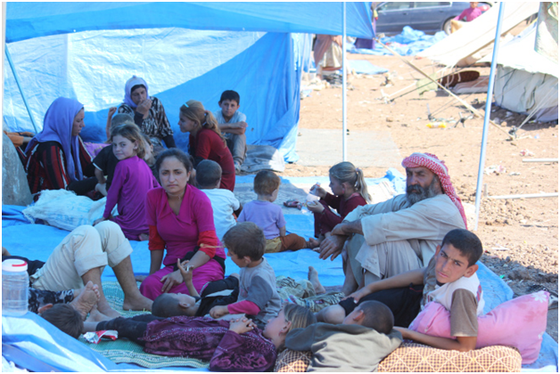 Des enfants et des familles yézidis se reposent à l’abri du soleil au camp pour personnes réfugiées de Nawrouz