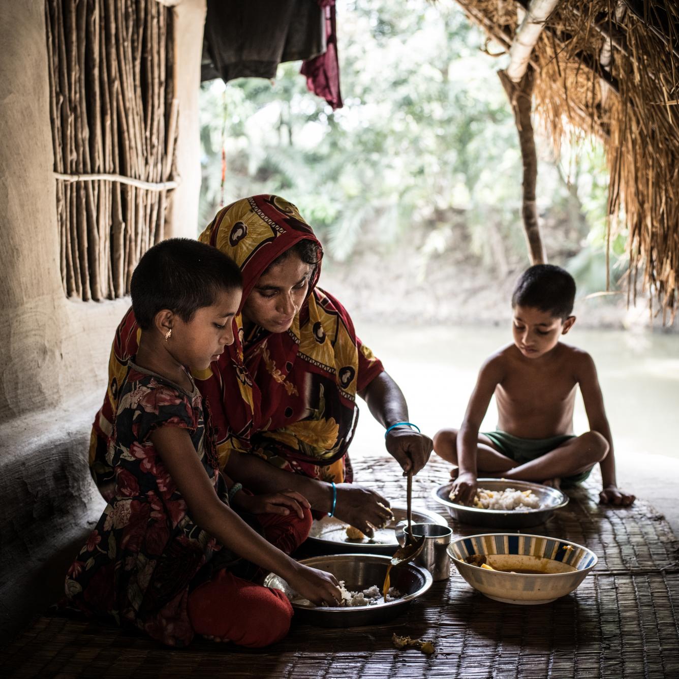 Rexona Begum, 30, the mother of Sumiya Mollah, 5, and Moriom Mollah, 6, eat a meal of curry potatoes and rice in Bangladesh.