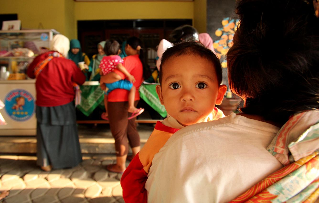 A boy carried by a woman is among young children accompanying adults at the Baby Café in Pandas Village, Indonesia.
