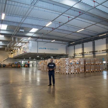 A man stands in a warehouse with lots of boxes behind him.