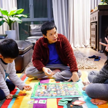 A family plays a board game at home together in Vietnam.