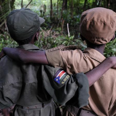 Two former child soldiers pose with their arms around each other.