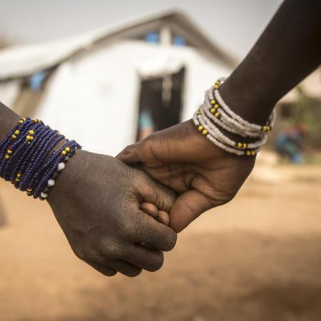 Two girls hold hands outside a UNICEF supported centre.