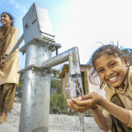A young girl pumps safe water for drinking in Rajasthan, India. 