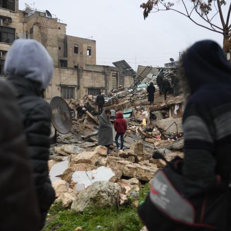 On 6 February 2023, people gather around collapsed buildings as rescue teams look for survivors following an earthquake in the government-held Syrian city of Aleppo. 