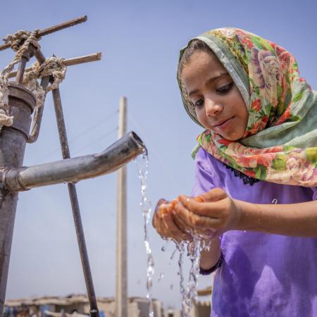 Nafisa (6) drinking water from a community handpump.