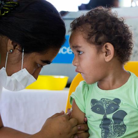 A little boy watches a nurse as he receives a vaccine shot.