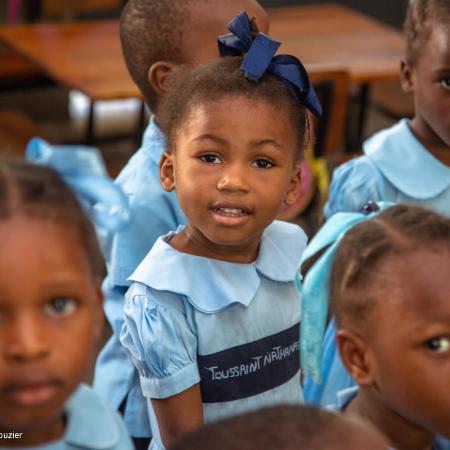 On 20 June 2023, students stand together during a visit by UNICEF Executive Director Catherine Russell and World Food Programme (WFP) Executive Director Cindy McCain to a UNICEF- and WFP-supported school in Port-au-Prince, Haiti.