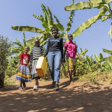 On 17 July 2023, UNICEF Goodwill Ambasador Vanessa Nakate walks with Adele (in pink), Graciella (in black and white stripes) and Bonette in Kigarama Sector, Kirehe District, Eastern Province of Rwanda.