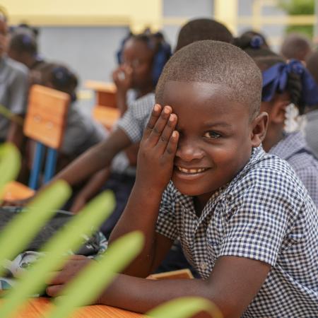 A young boy smiles during the inauguration ceremony of his school in Maingrette.