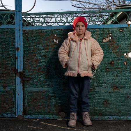 Un enfant ukrainien regarde l’objectif, vêtu d’une veste d’hiver et d’une tuque rouge.
