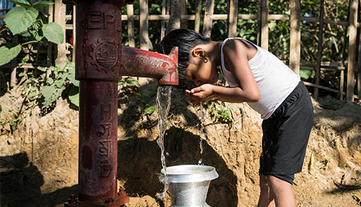 Boy drinking water from a pump