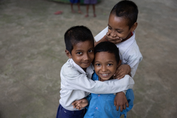 Three boys in India hugging and smiling