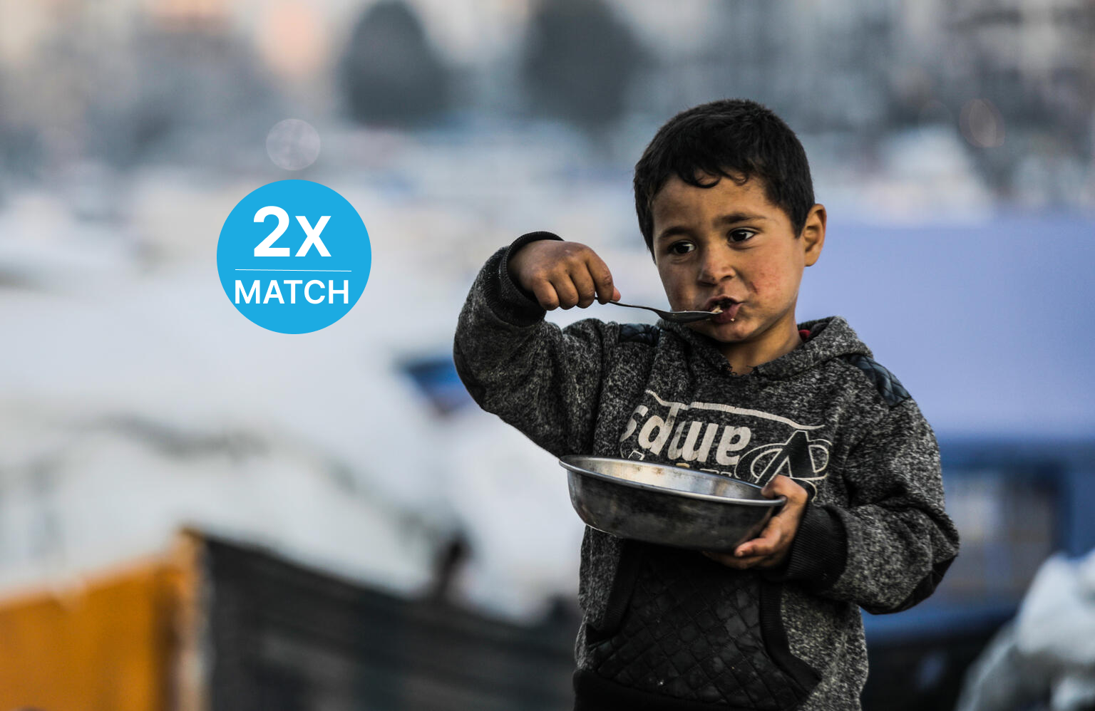 Young boy from Gaza City eating his meal out of a metal bowl.