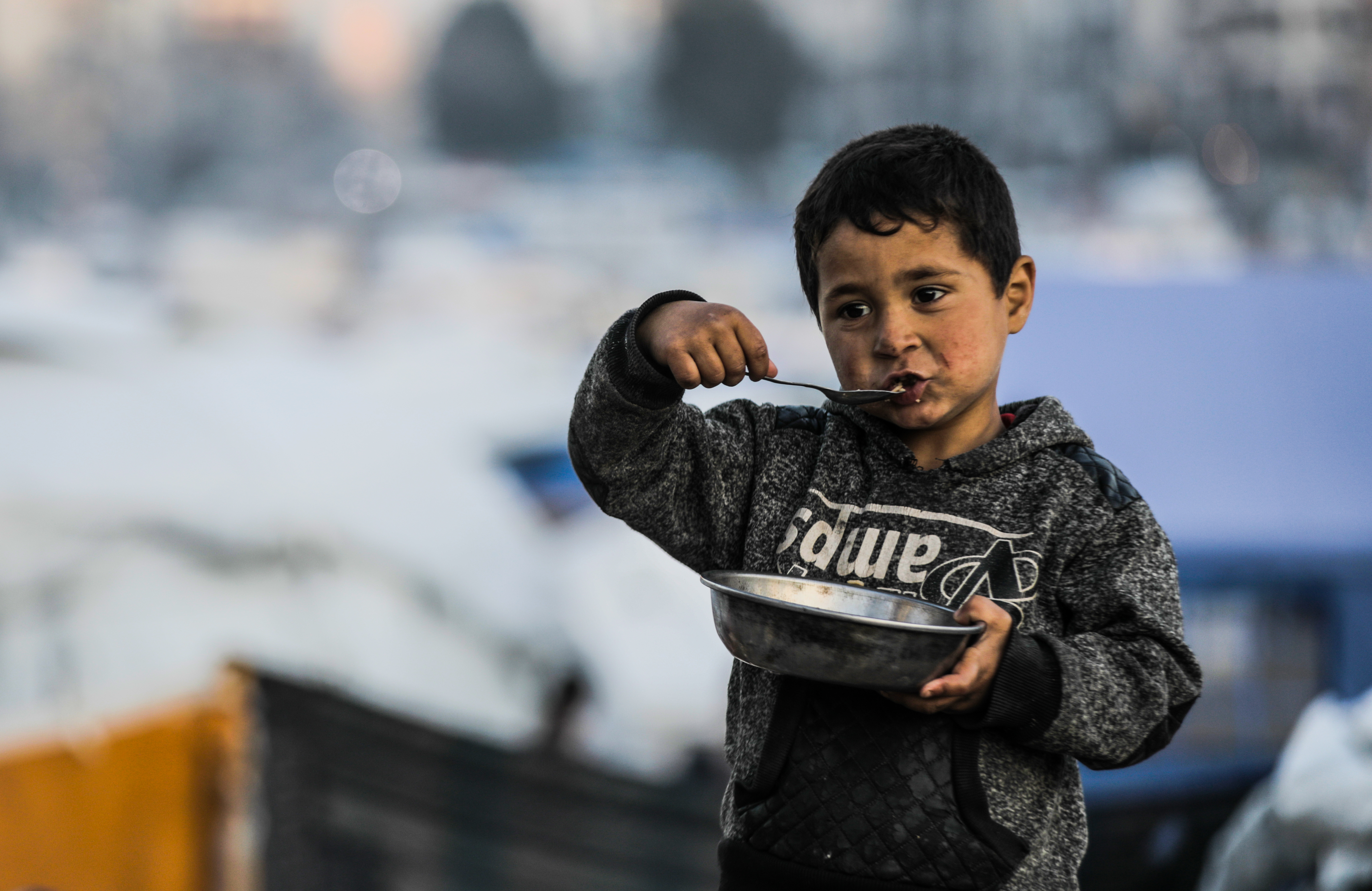 Young boy from Gaza City eating his meal out of a metal bowl.