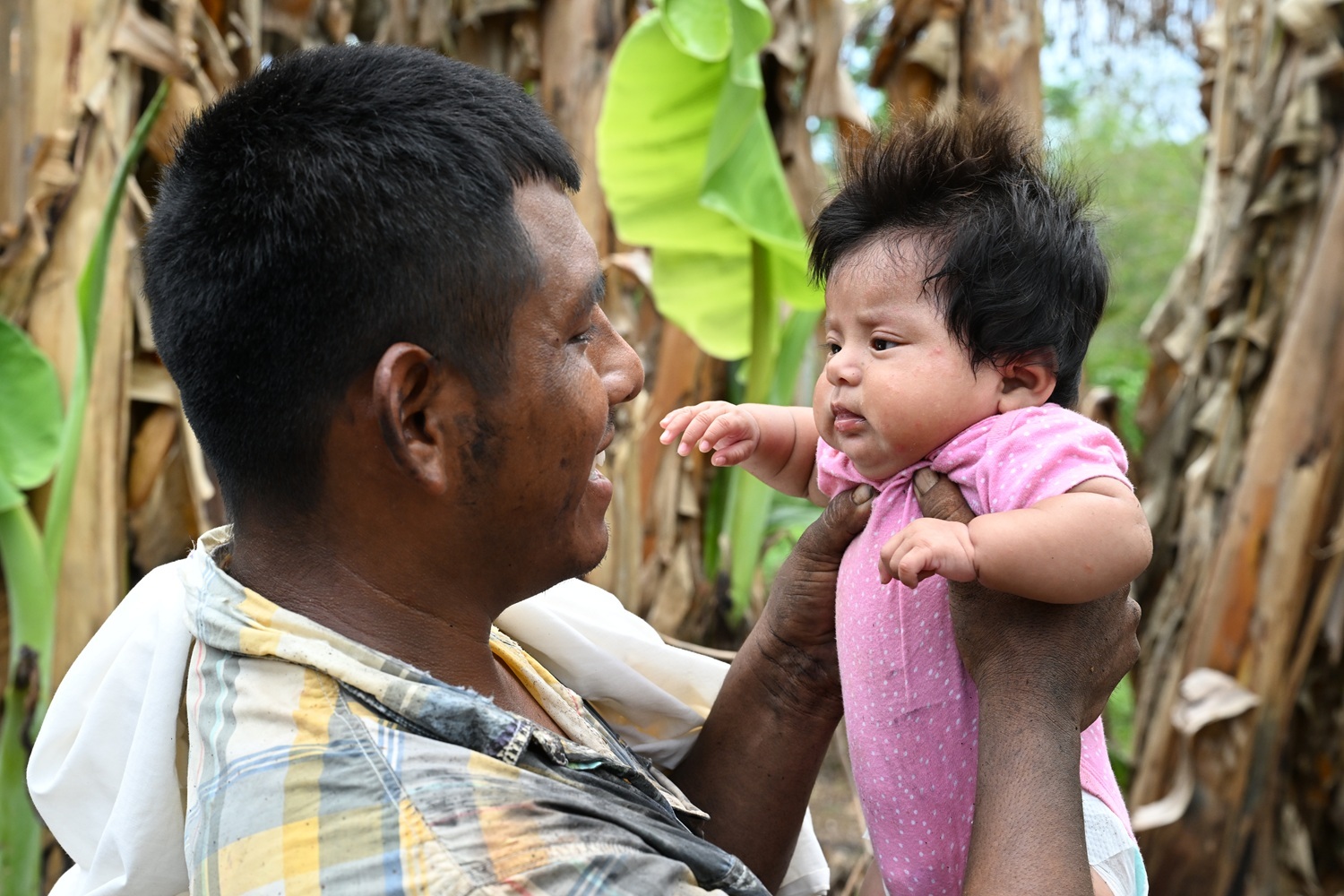 A smiling father holds his baby.