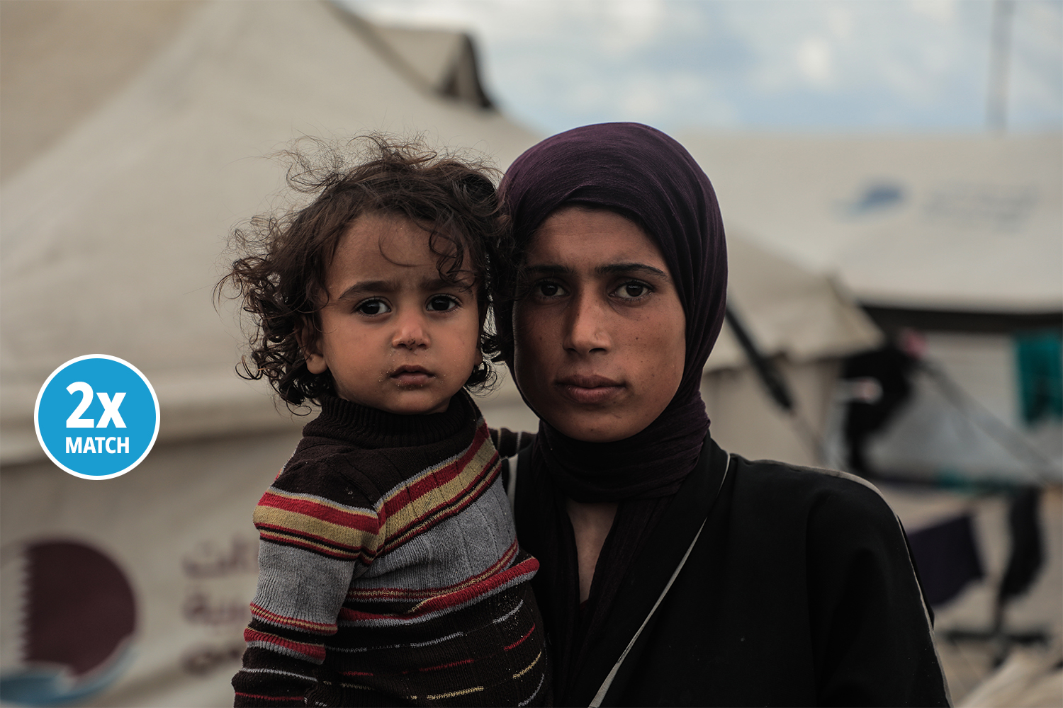 In Gaza city, a mother holds her daughter close as she looks at the camera.