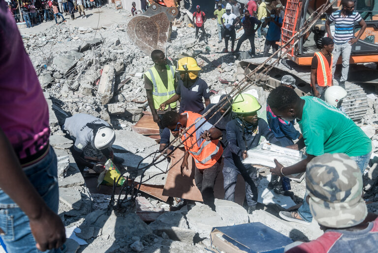 People look for survivors amongst the rubble in the neighbourhood of Dexia 6, Les Cayes, Haiti on August 15, 2021, after a 7.2-magnitude earthquake struck the southwest peninsula of the country. - Hunched on benches, curled up in chairs or even lying the floor, those injured in the powerful earthquake that wreaked havoc on Haiti on Saturday crowded an overburdened hospital near the epicenter. The emergency room in Les Cayes, in southwestern Haiti, which was devastated by the 7.2-magnitude quake on Saturday morning that killed at least 724 people, is expecting reinforcements to help treat some of the thousands of injured.