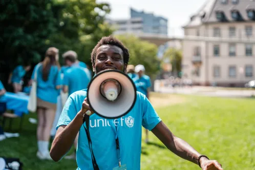 Un jeune portant un t-shirt bleu de l’UNICEF parle dans un mégaphone.