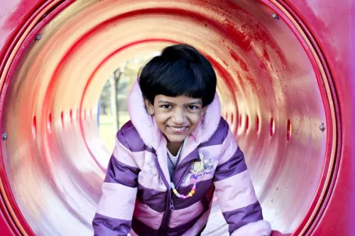 Une jeune fille est représentée dans un tunnel rouge sur une aire de jeux.