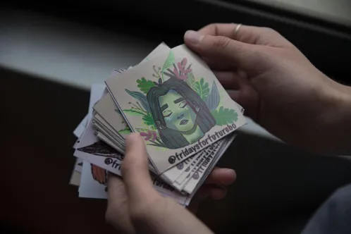 A youth holds stickers with the hashtag Fridays for Future printed on them.