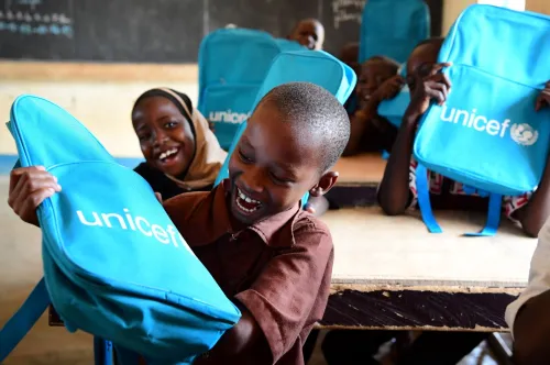 In Niger, excited schoolchildren smile and laugh at their desks after receiving UNICEF school backpacks.