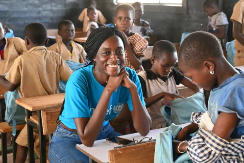 A UNICEF worker smiles while seated among students at a school in Côte d’Ivoire.
