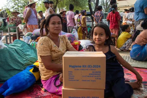 Une femme et une enfant sont assises, des boîtes de trousses d’hygiène de l’UNICEF posées devant elles, dans la région de Sagaing, à la suite du séisme de magnitude 7,7 qui a secoué le Myanmar.
