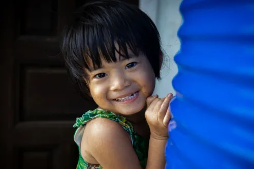Portrait en gros plan d’une jeune fille souriant à l’objectif à côté d’un réservoir d’eau bleu.