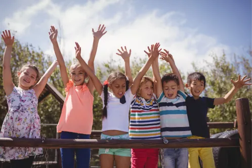 Children smiling with their hands raised in the air. 