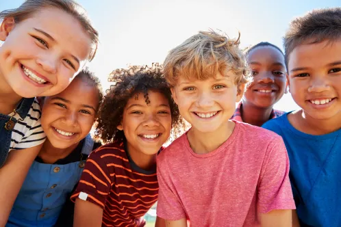A group of children from diverse backgrounds smile at the camera. 
