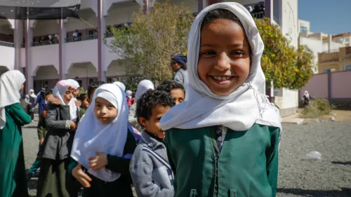 Une jeune fille sourit, entourée des élèves d’une école secondaire au Yémen.