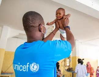 un bébé tenu par un représentant de l'UNICEF