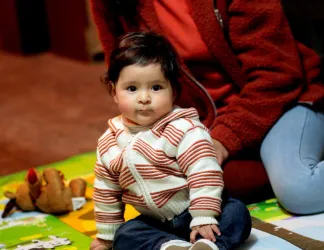 A mother and her child sitting on the floor reading a picture book.