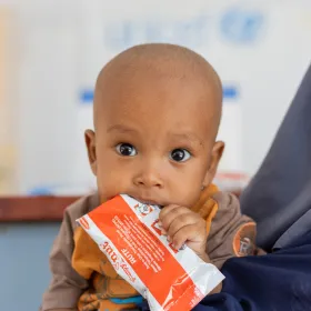 Baby chewing on a Plumpy'Nut therapeutic food packet.