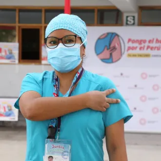 A health worker gives the V for Vaccinated sign after receiving their first COVID-19 vaccine in Peru.