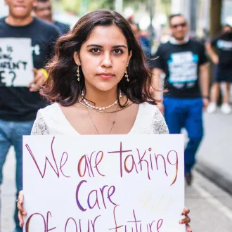 Sophia, 18, carries a sign at a protest that reads “We are taking care of our future.