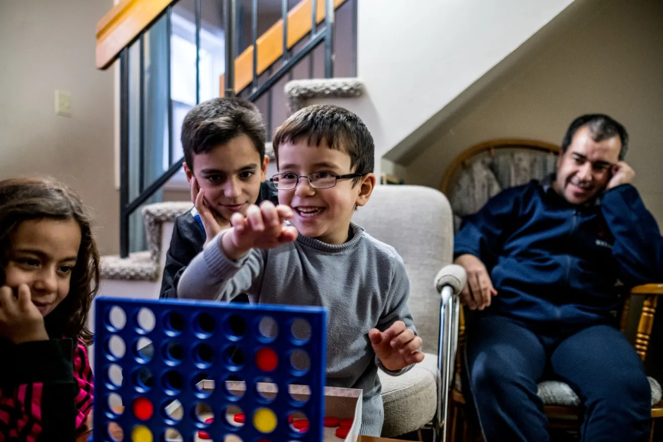 (Left-right) Shatha, 7, Basil, and Idress, 5, relax at home with their father.