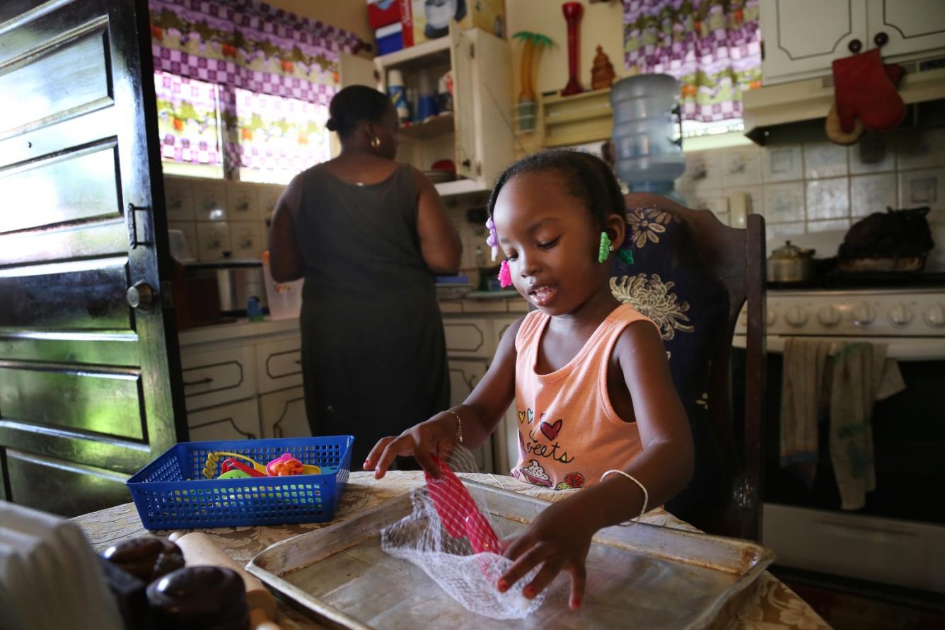 Alishia, in the kitchen with her mother, Keisha Gentle, plays with toy utensils.