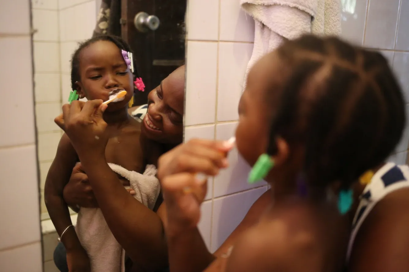 Keisha Gentle — teaching her daughter, 3-year-old Alishia, how to brush her teeth .