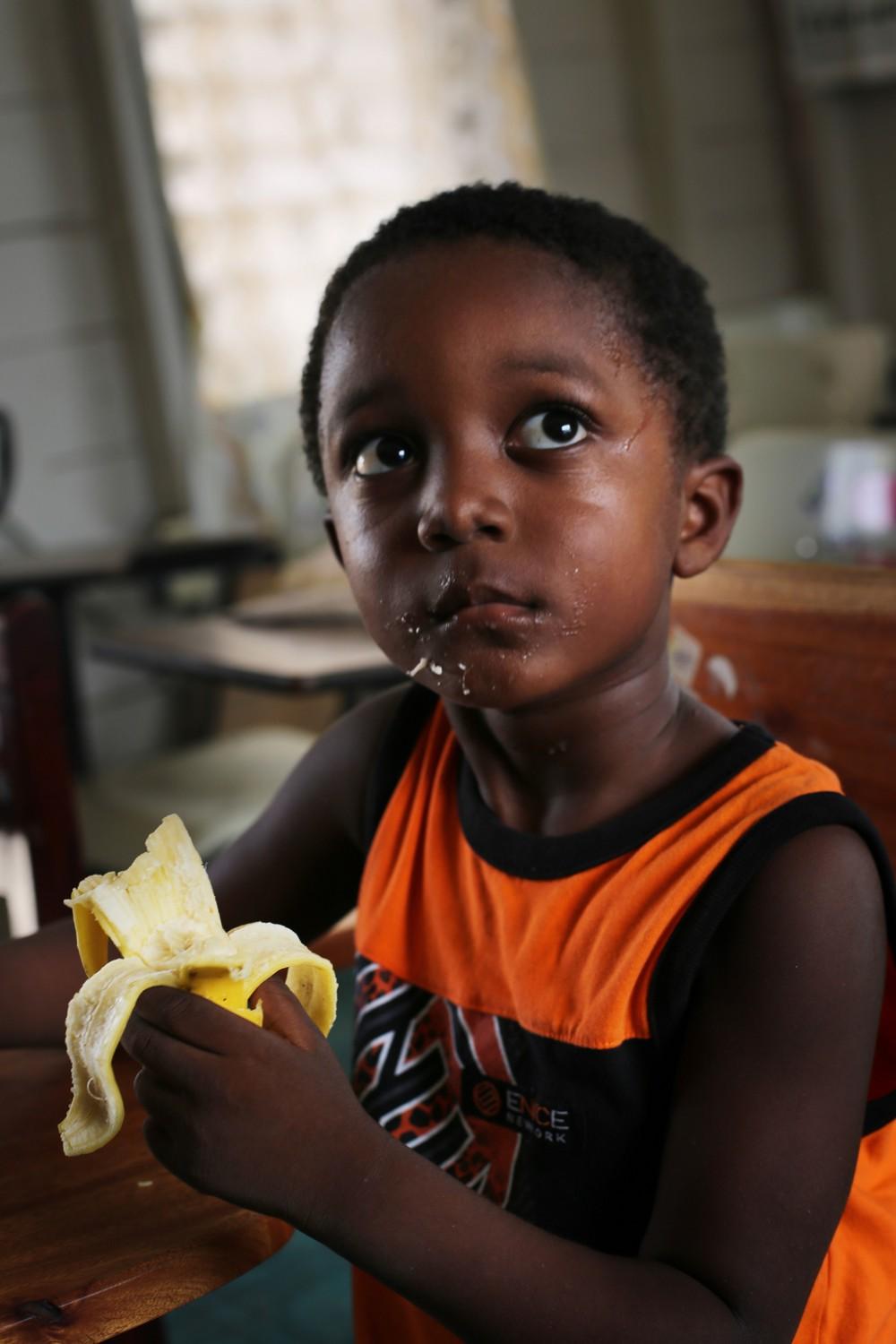 Orin eats fruit in his father’s preschool classroom, in Dangriga Town.