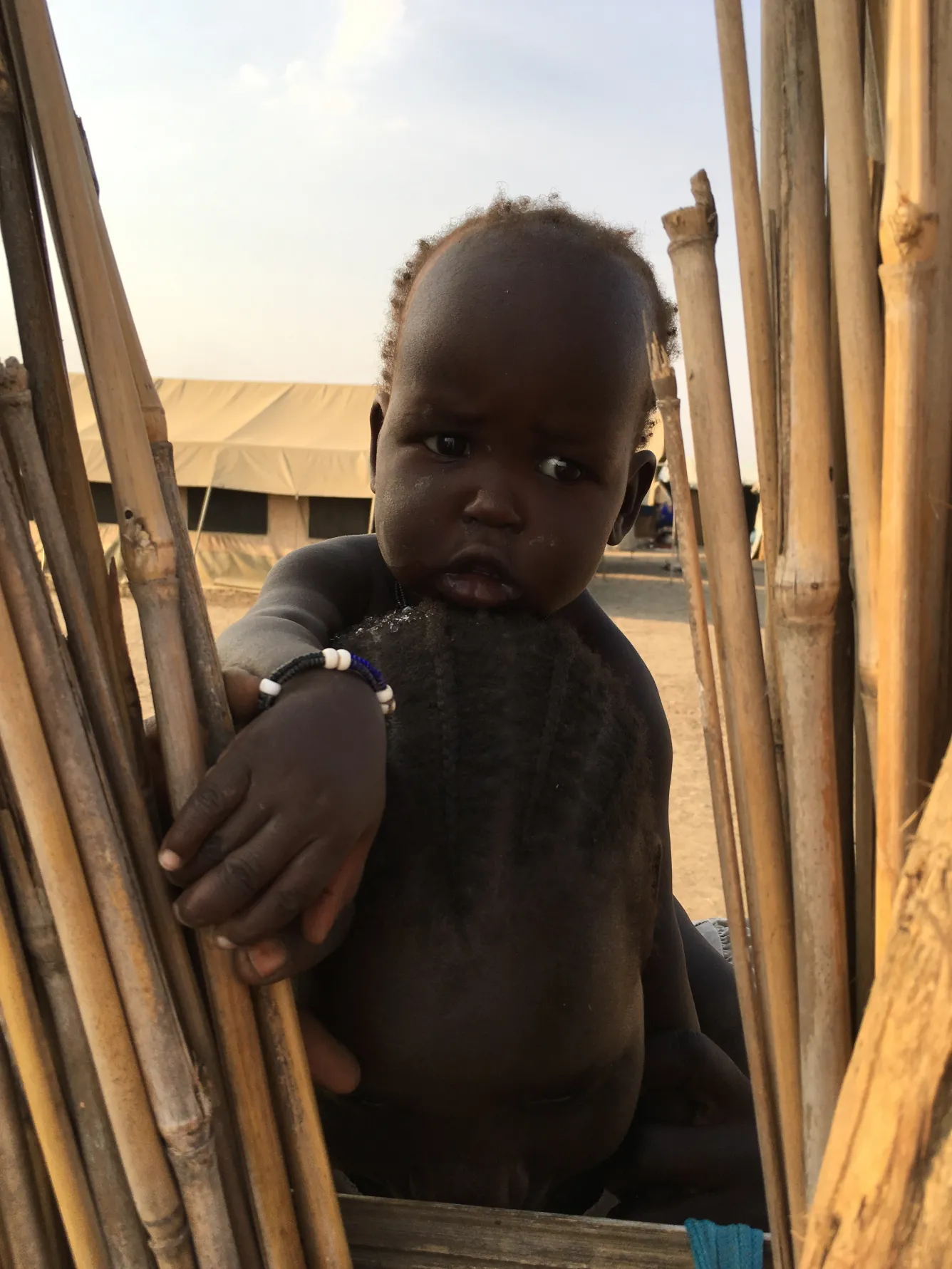 A young child peers through the fence at a UNICEF-supported school in Bentiu.