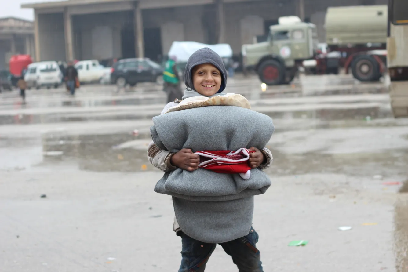 A girl holds the new blankets and winter clothing she was given to help protect her from the now freezing temperatures at the Jibreen shelter. 