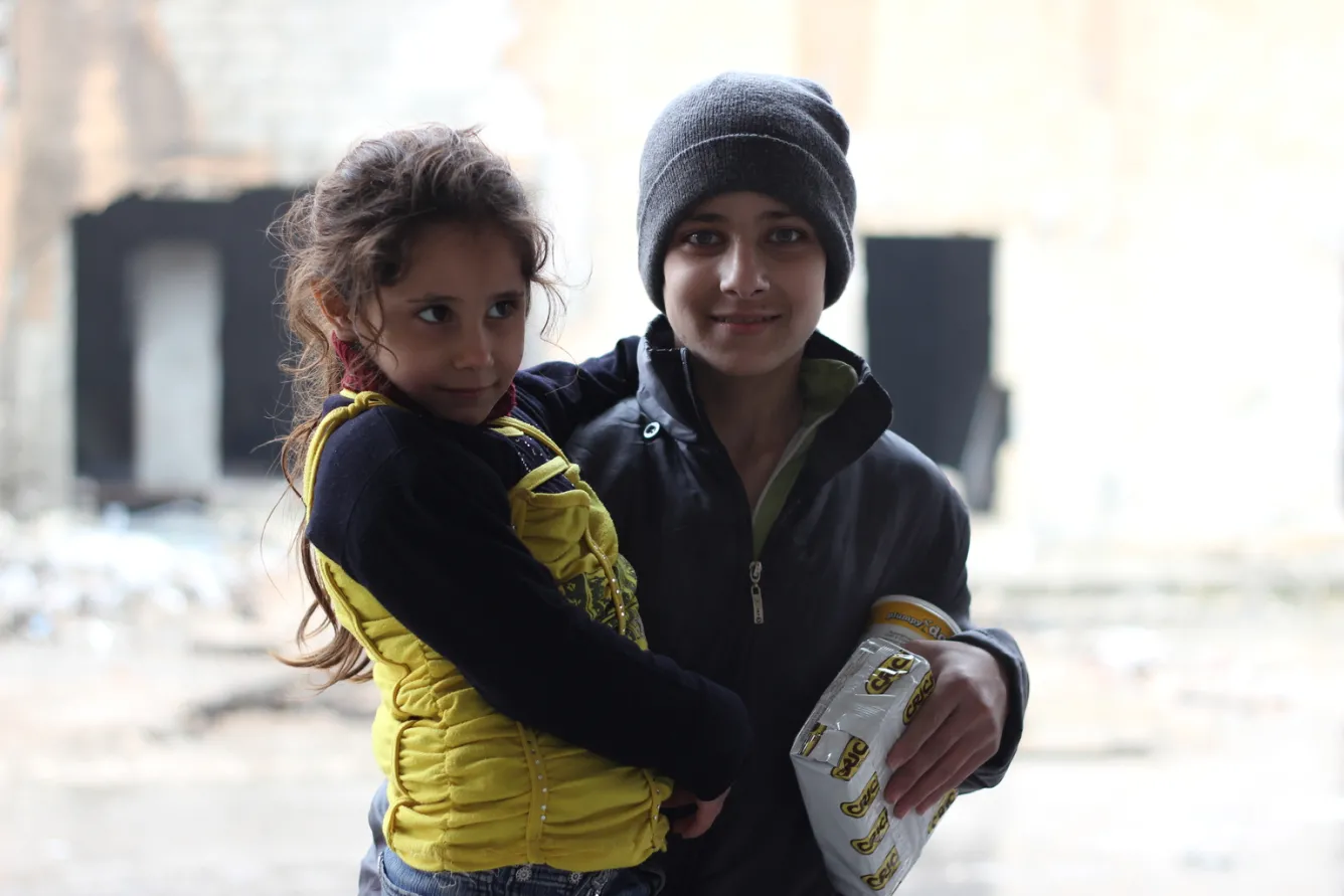 A child holds a box of high-energy biscuits that are being distributed by UNICEF to children in a large warehouse in Jibreen.