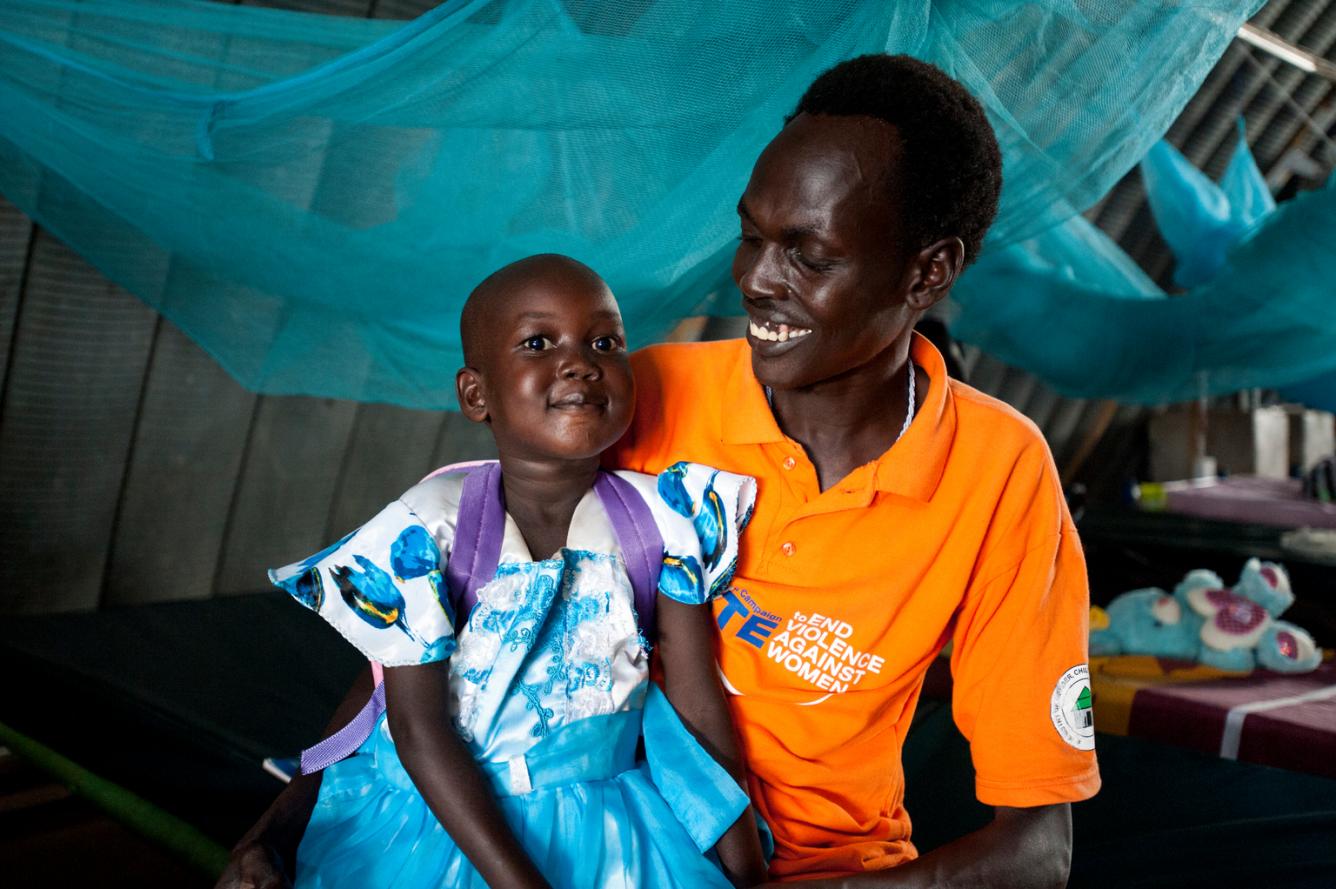 Nyajime sits with her father in a UNICEF-supported health centre