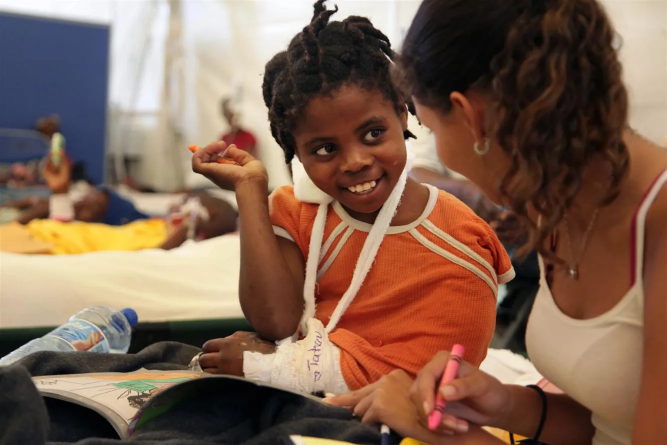 Marie Yolene Milord, 9 ans, est travailleuse domestique. Elle discute avec une bénévole dans un hôpital de Port-au-Prince. Elle aimerait retourner dans son village natal, Les Cayes : « Ma mère est morte, mais je pense que mon père est toujours vivant. Si vous m’amenez là-bas, je pourrai reconnaître ma maison. Je veux juste retourner à la maison. » © UNICEF/UNI78171/LeMoyne