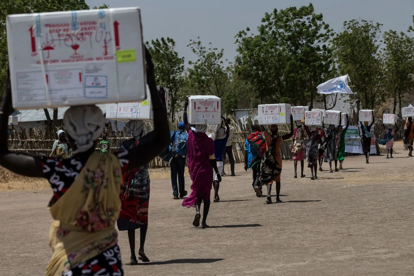 Women carry newly-arrived boxes full of life-saving vaccines in South Sudan