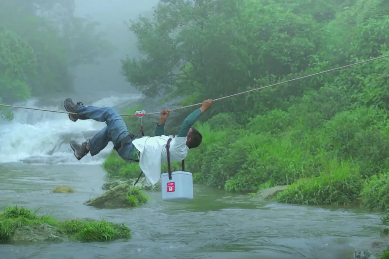 A vaccine carrier is carefully transported across a river in India.