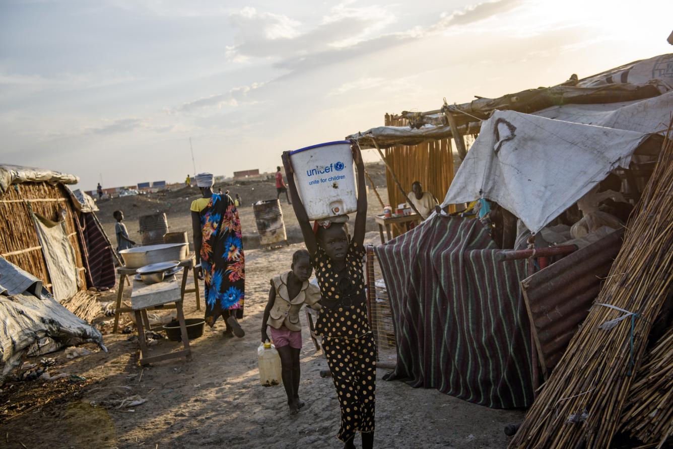 a girl carries a bucket filled with safe drinking water